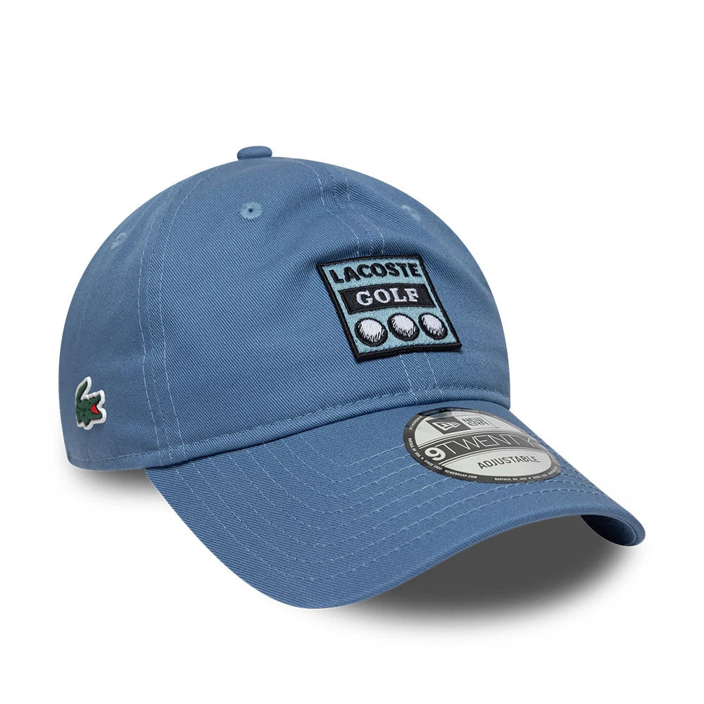 Lacoste X New Era Blue 9TWENTY Adjustable Cap, front view showing a prominent Lacoste Golf patch with three golf ball graphics on the front panel, a green Lacoste logo on the left side, and a grey 9TWENTY size sticker on the curved visor.
