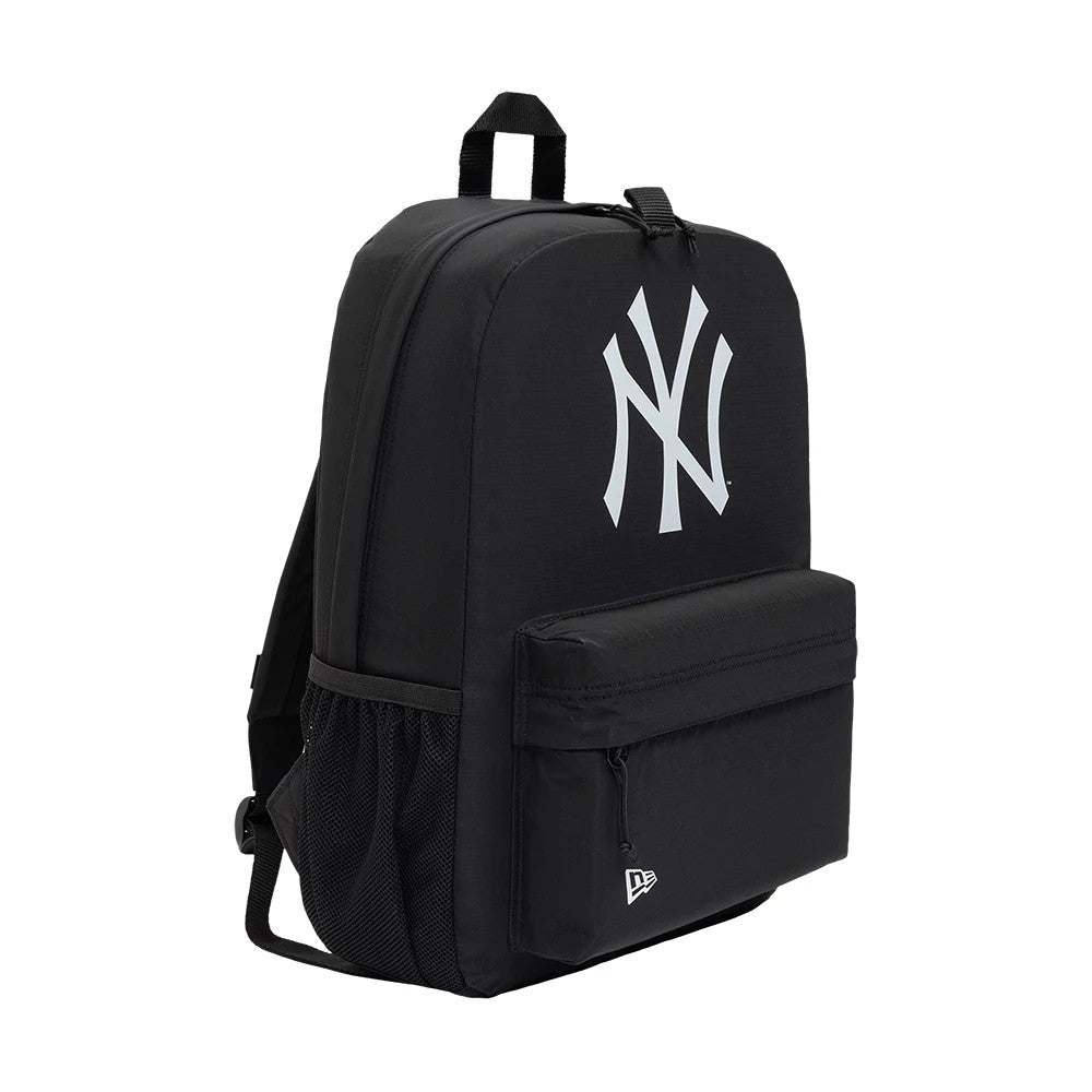New Era New York Yankees MLB Sport Black Smart Backpack, three-quarter view displaying a large white printed Yankees logo on the upper front, a zippered front pocket with a small embroidered New Era logo, and a side mesh pocket.