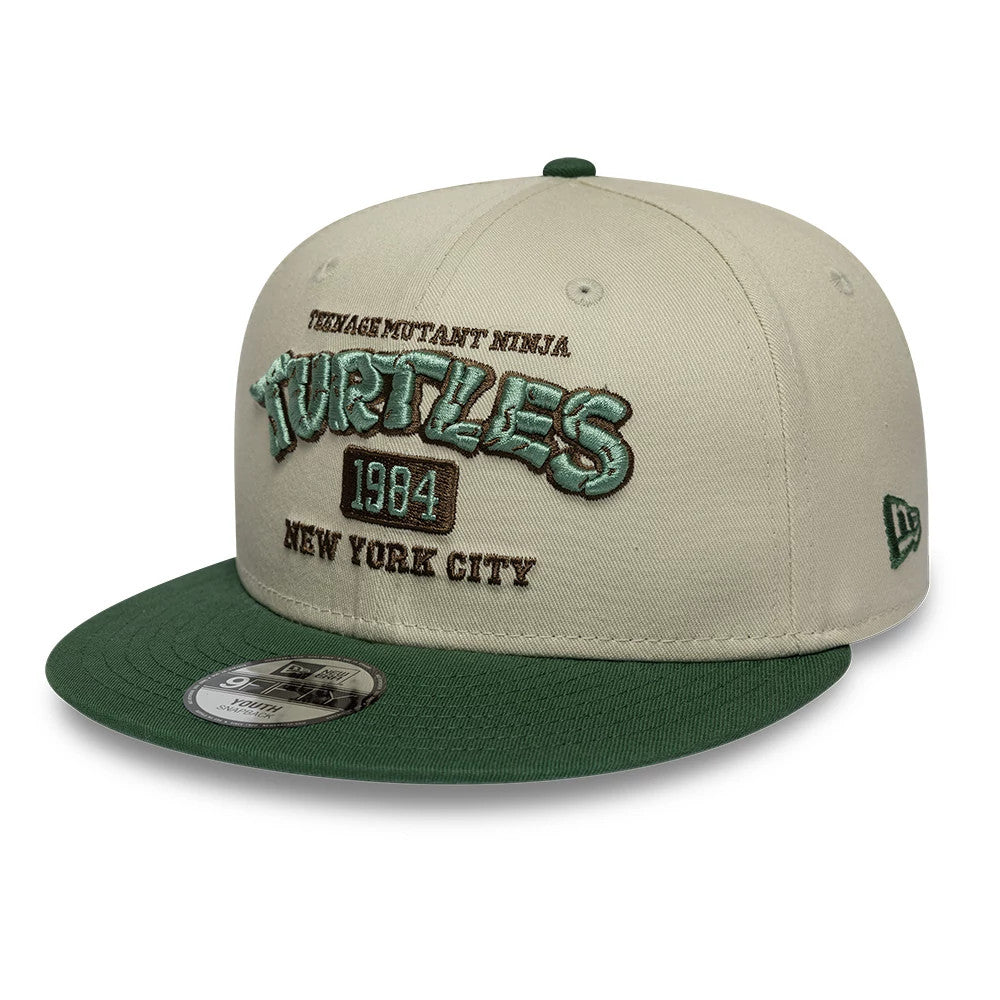 Youth Teenage Mutant Ninja Turtles Beige New Era 9FIFTY Snapback Adjustable Cap, front view showing green raised Teenage Mutant Ninja Turtles logo embroidered on the beige crown, with a matching green flat visor and 9FIFTY size sticker.