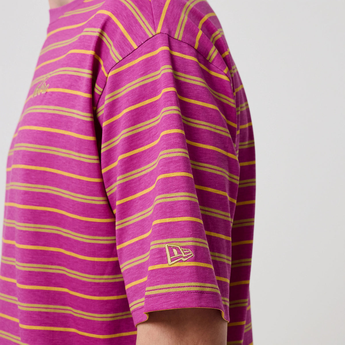New Era Stripe Bright Purple T-Shirt, side view showing a purple base with yellow and pink horizontal stripes, a embroidered New Era logo at the sleeve's edge, and a closer look at the crew neckline and stitching details.