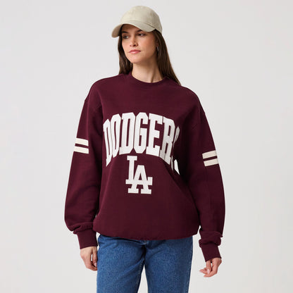 New Era LA Dodgers MLB Arch Graphic Dark Purple Crew Neck Sweater, front view on a model with a neutral baseball cap, showcasing white Dodgers lettering arching over LA on the chest and striped sleeve details for a sporty look.