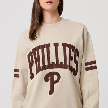New Era Philadelphia Phillies MLB Arch Graphic Light Beige Crew Neck Sweater, front view on a model showcasing the brown PHILLIES text in arch embroidery across the chest, with matching double-stripe on both sleeves.