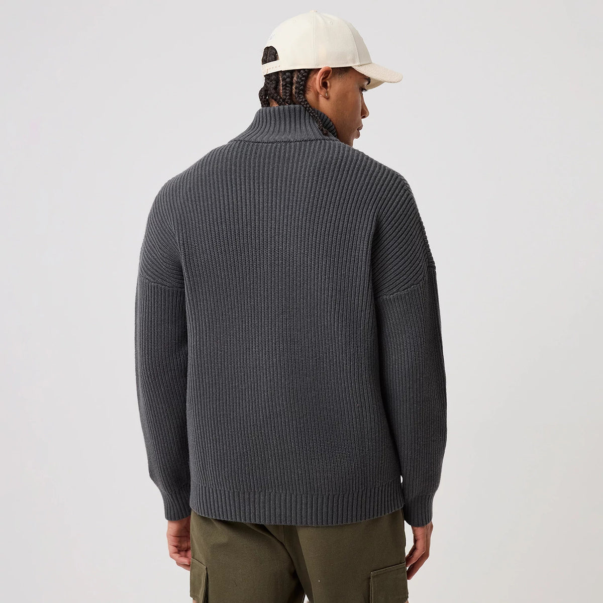 New Era New York Mets MLB Charcoal 2 Way Zip Cardigan, back view on a model showing the ribbed texture that covers the entire cardigan, with a high collar and long sleeves, contrasted with green cargo trousers.