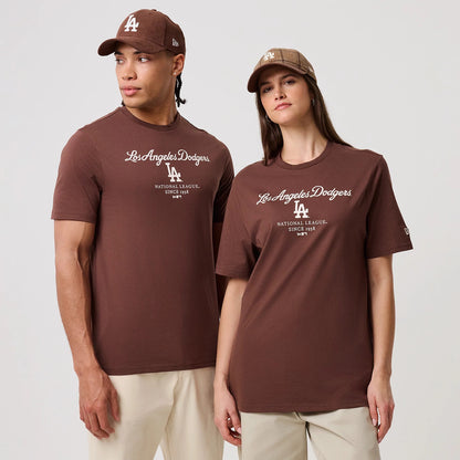 New Era LA Dodgers MLB Linear Brown T-Shirt, front view on-model showing the brown T-shirt with white printed Los Angeles Dodgers script across the chest, LA logo below it, and New Era flag logo on the left sleeve, styled with caps.