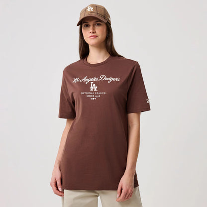 New Era LA Dodgers MLB Linear Brown T-Shirt, front view on a model, featuring the white embroidered Los Angeles Dodgers script logo across the chest and a small embroidered New Era logo on the left sleeve, styled with a matching cap.