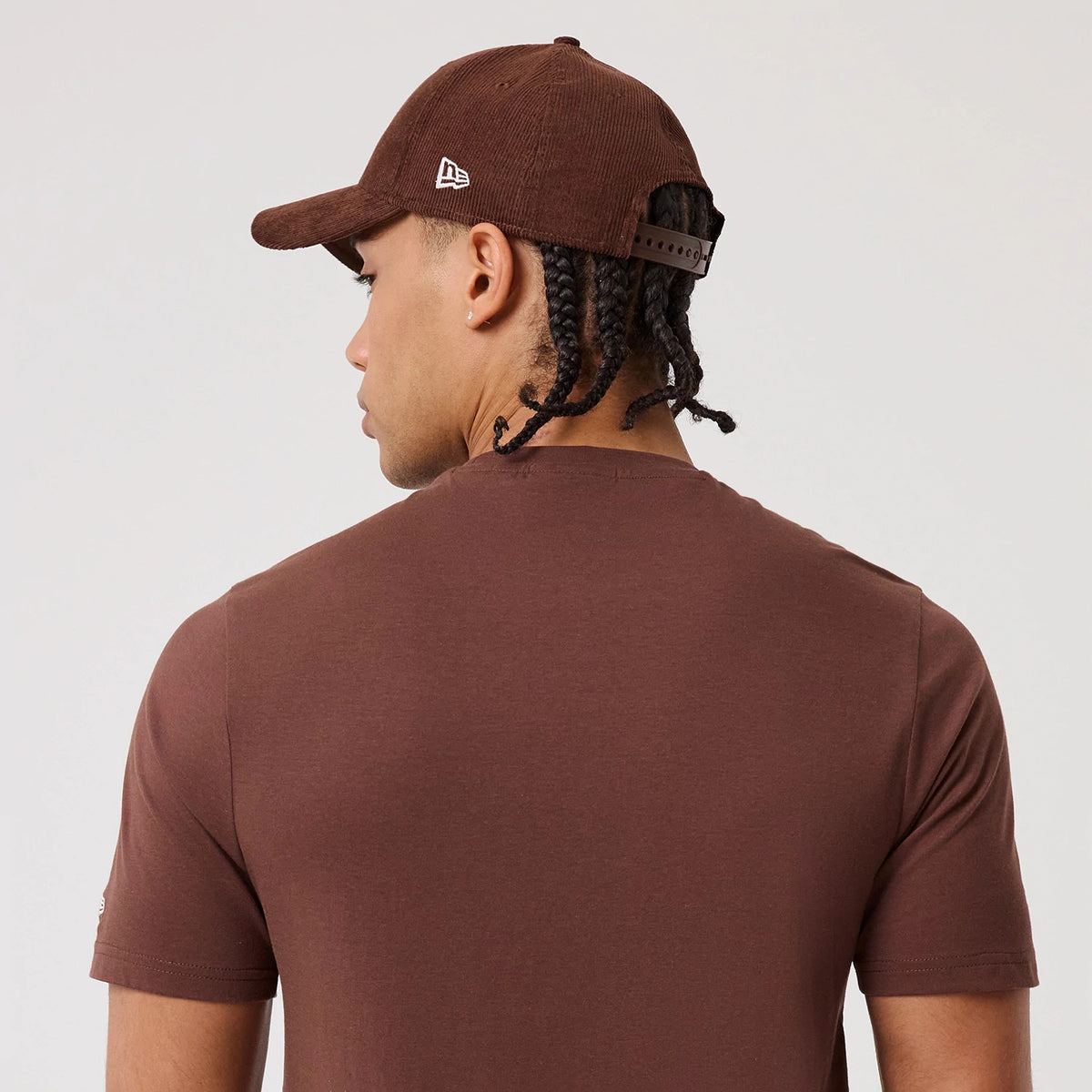 New Era LA Dodgers MLB Linear Brown T-Shirt, back view on-model showing the plain brown back of the T-shirt, with an embroidered New Era logo on a matching brown cap worn backwards, highlighting the T-shirt's solid colour and casual fit.