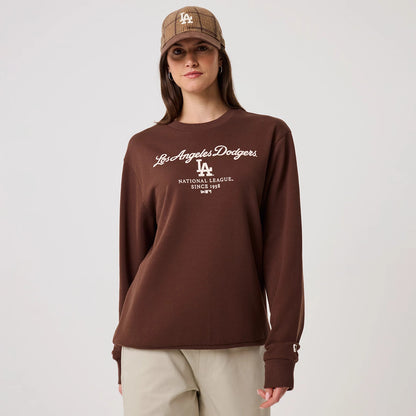 New Era LA Dodgers MLB Linear Brown Crew Neck Sweater, front view on a model with a brown Los Angeles Dodgers cap, featuring white Los Angeles Dodgers script and logo across the chest, ribbed cuffs with a small B logo detail.
