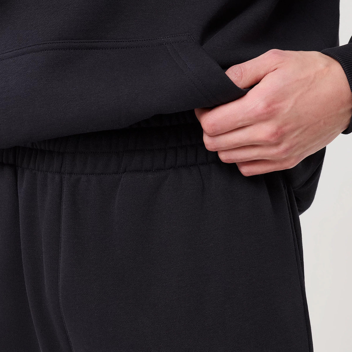 New Era Navy Straight Leg Joggers, close-up view showing the elasticated waistband being adjusted by a hand, detailed with a textured fabric and a appearance of the upper pocket section.