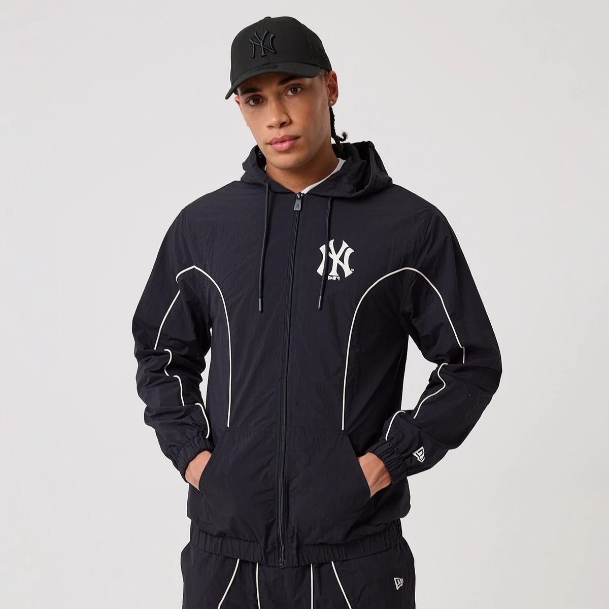 New Era New York Yankees MLB Piping Navy Track Jacket, front view on-model featuring a large embroidered Yankees logo on the chest, contrasting white piping along the arms and body, and a small embroidered New Era logo near the left wrist.
