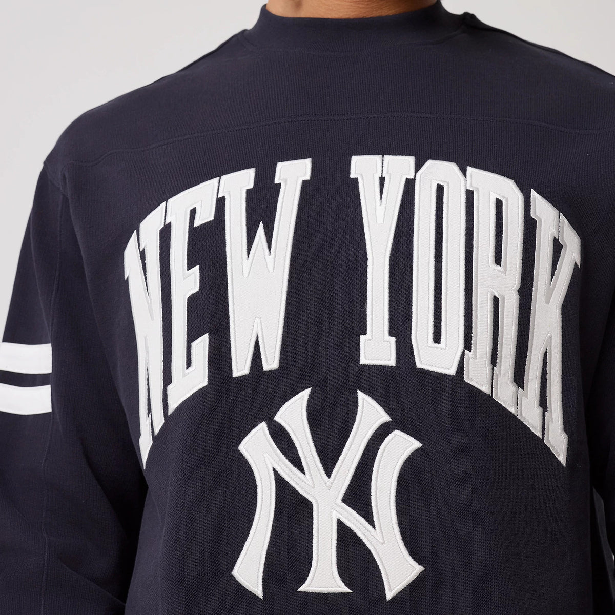 The model is wearing this MLB Arch Graphic New York Yankees Crew Neck Sweater in navy. 5