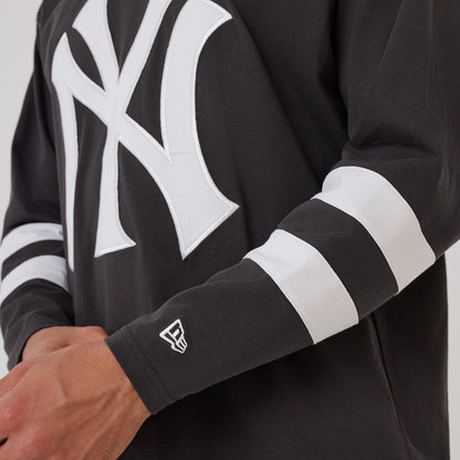 The model is wearing this MLB League Essential New York Yankees Oversized Jersey in charcoal. 5