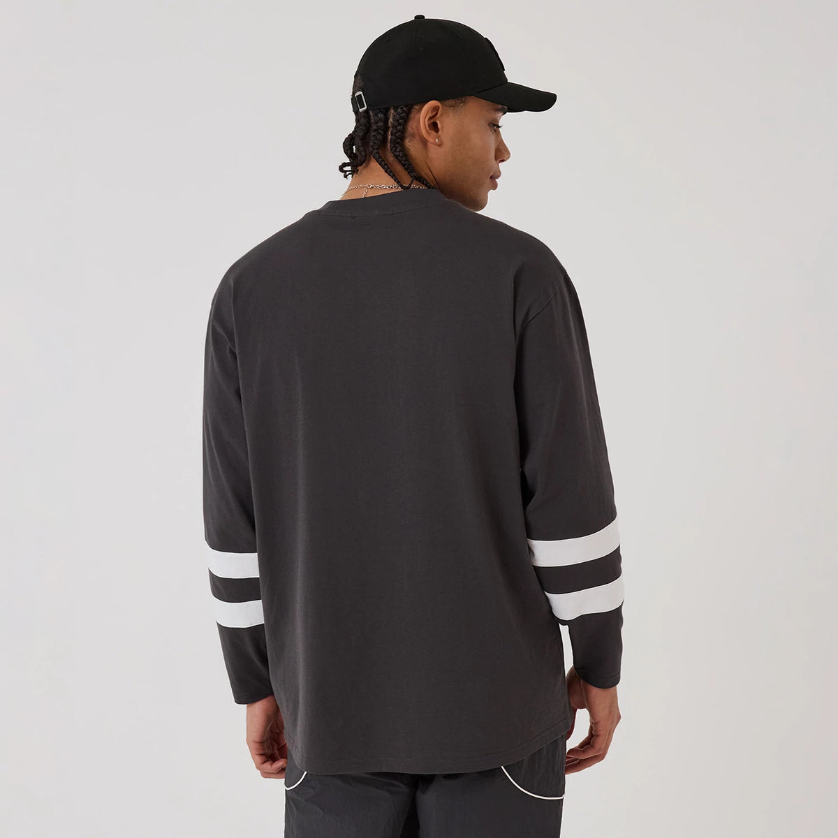 New Era New York Yankees MLB League Essential Charcoal Oversized Jersey, back view on a model wearing a black cap, showcasing the jersey's simple charcoal design with two white horizontal stripes on each sleeve.