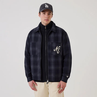 New Era Navy Shacket, front view on a model wearing a dark cap, featuring a navy plaid pattern, an embroidered NE logo on the left chest pocket, and a New Era flag logo on the left sleeve cuff.