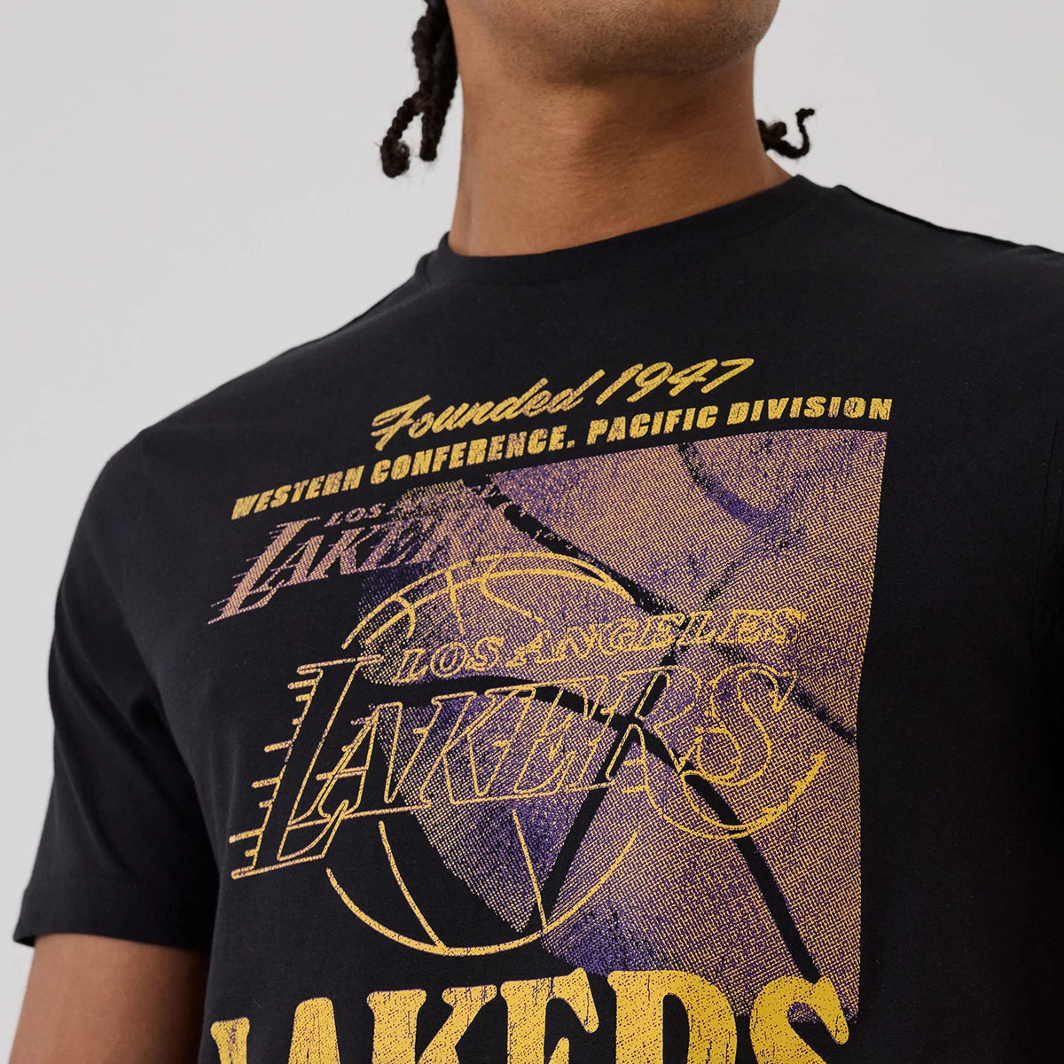 New Era LA Lakers NBA Graphic Black T-Shirt, front view featuring a large printed design across the chest with Founded 1947, Western Conference, Pacific Division, and Los Angeles Lakers text in yellow and purple on a black backdrop.