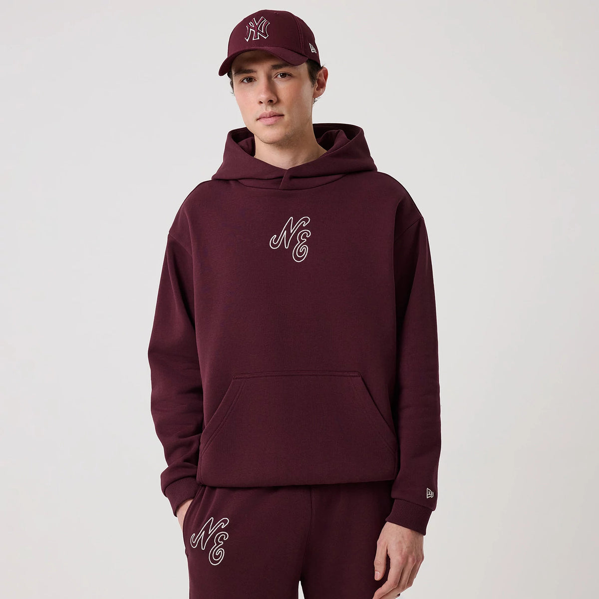 The model is wearing this New Era Crest Graphic Pullover Hoodie in dark purple. 3