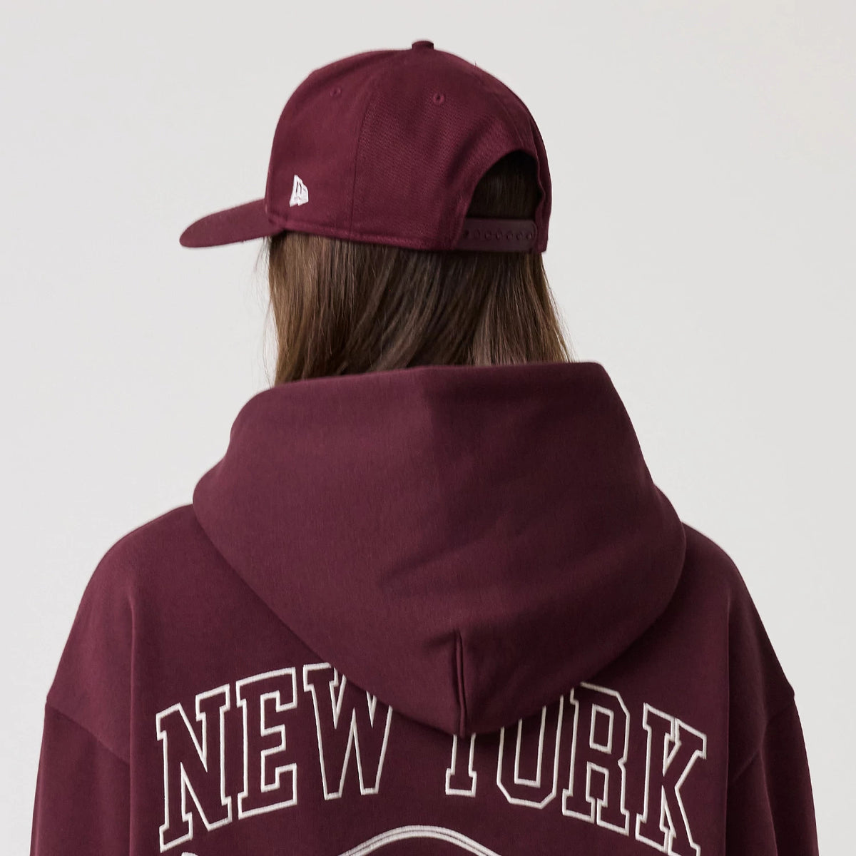 The model is wearing this New Era Crest Graphic Pullover Hoodie in dark purple. 6
