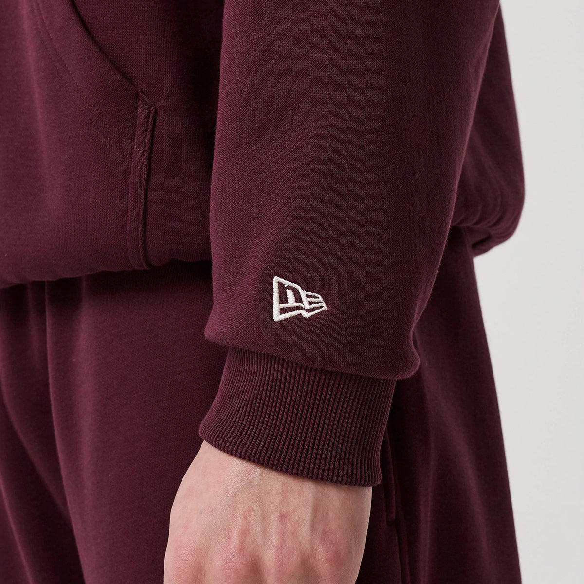 The model is wearing this New Era Crest Graphic Pullover Hoodie in dark purple. 7
