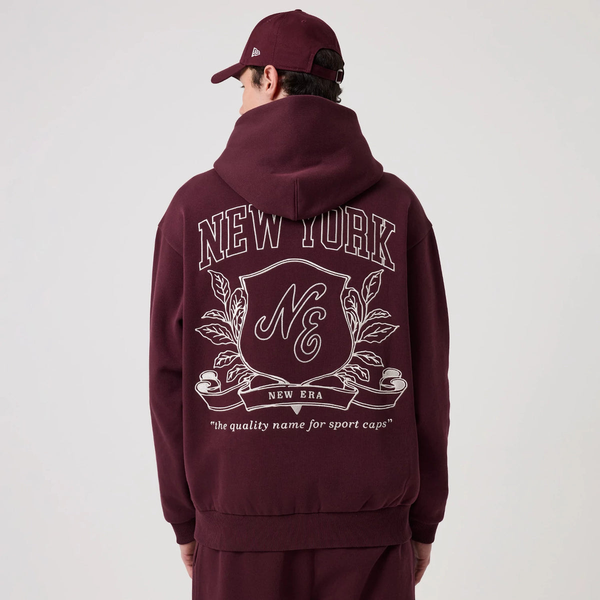 The model is wearing this New Era Crest Graphic Pullover Hoodie in dark purple. 2