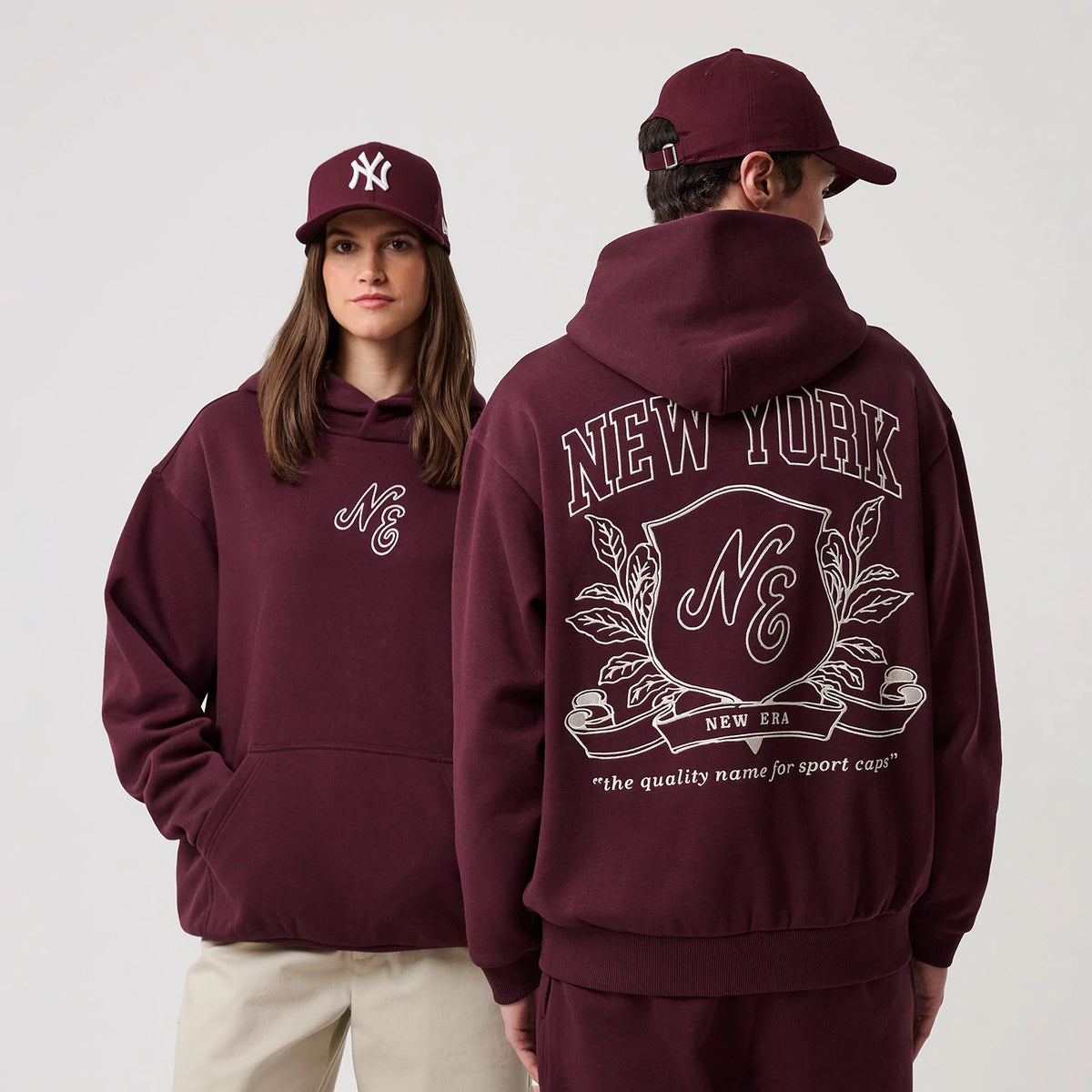 The model is wearing this New Era Crest Graphic Pullover Hoodie in dark purple. 1