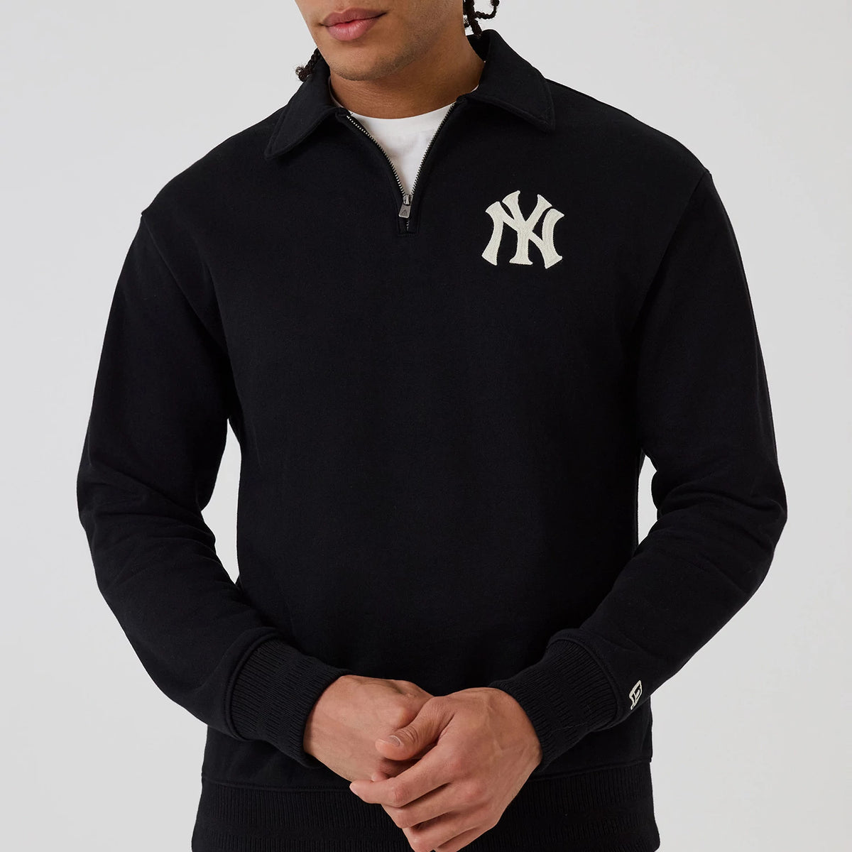 New Era New York Yankees MLB Black 1/4 Zip Sweater, front view on a model showing the white NY logo embroidered on the left chest, a half-zip closure with a collar, and the New Era flag logo above the left cuff.