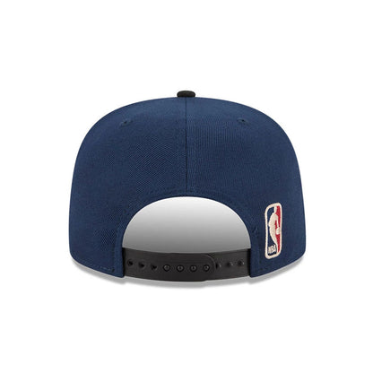 New York Knicks NBA Tip Off 2026 Dark Blue New Era 9FIFTY A-Frame Snapback Adjustable Cap, rear view showing the NBA logo embroidered on the left side of the dark blue structured crown, along with the black snapback closure.