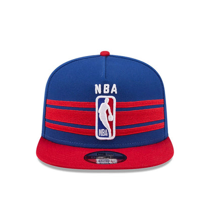 NBA Logo NBA Tip Off 2026 Blue New Era 9FIFTY A-Frame Snapback Adjustable Cap, front view showing the raised white NBA logo embroidered on the structured blue crown with red horizontal stripes and a red flat visor, featuring a 9FIFTY size sticker.