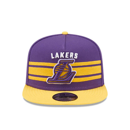 LA Lakers NBA Tip Off 2026 Purple New Era 9FIFTY A-Frame Snapback Adjustable Cap, front view showing raised yellow Lakers logo below white text on purple crown, with two yellow horizontal stripes and a contrasting yellow visor.