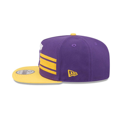 LA Lakers NBA Tip Off 2026 Purple New Era 9FIFTY A-Frame Snapback Adjustable Cap, side view showing the yellow embroidered New Era flag logo on the left side, contrasting purple crown with gold stripes.