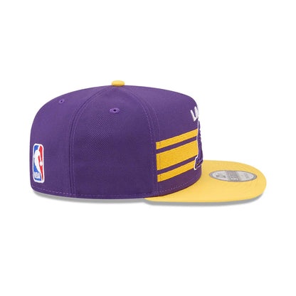 LA Lakers NBA Tip Off 2026 Purple New Era 9FIFTY A-Frame Snapback Adjustable Cap, side view showing the NBA logo embroidered on the left side, a prominent structured purple crown, and a contrasting yellow flat visor with a 9FIFTY size sticker.