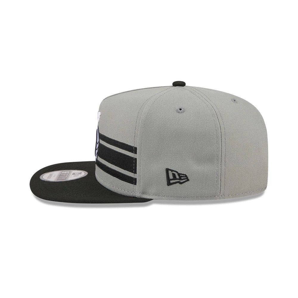 Brooklyn Nets NBA Tip Off 2026 Dark Grey New Era 9FIFTY A-Frame Snapback Adjustable Cap, side view showing the New Era flag logo on the grey crown, with black parallel stripes, and a flat black visor with a grey 9FIFTY size sticker.