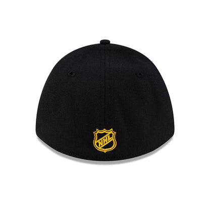 Boston Bruins NHL Team Black New Era 39THIRTY M-Crown Stretch Fit Cap, rear view showing the gold embroidered NHL shield logo centred on the back panel, with black eyelets and a rounded black crown.