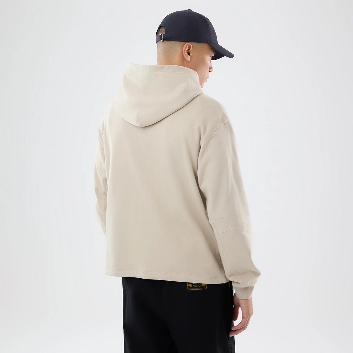 The model is wearing this New Era Open Hem Pullover Hoodie in light beige. 2