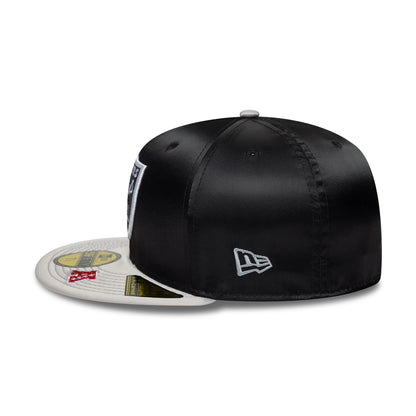 LA Raiders NFL Satin Black & Grey New Era 59FIFTY Fitted Cap, side view showing the raised white and grey embroidered New Era flag logo on the left side, with a black satin crown and flat grey visor featuring multiple size stickers.