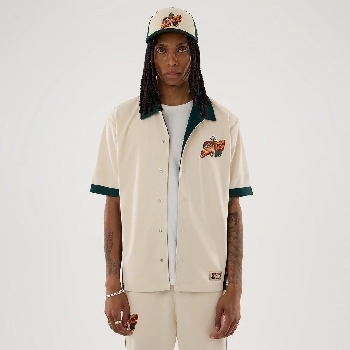 The model is wearing this NBA Hardwood Classic Revere Seattle Supersonics Short Sleeve Shirt in light beige. 1