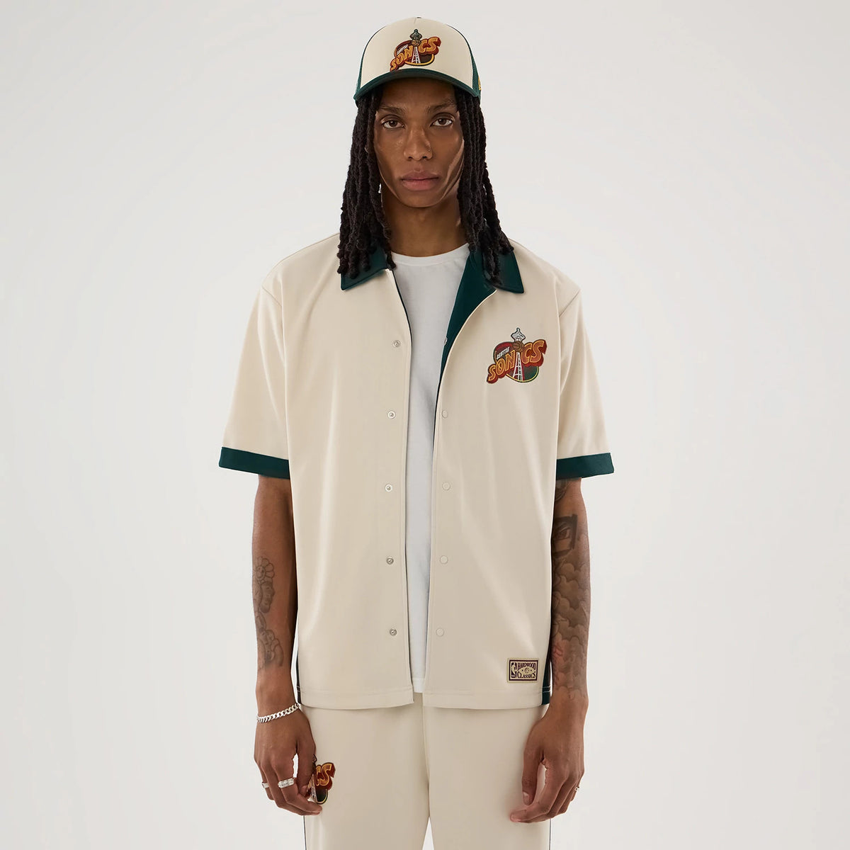 The model is wearing this NBA Hardwood Classic Revere Seattle Supersonics Short Sleeve Shirt in light beige. 1
