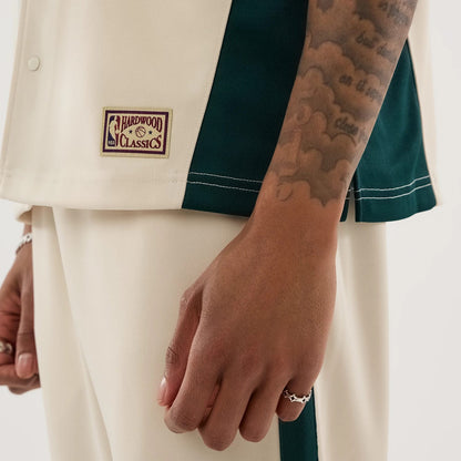 The model is wearing this NBA Hardwood Classic Revere Seattle Supersonics Short Sleeve Shirt in light beige. 6