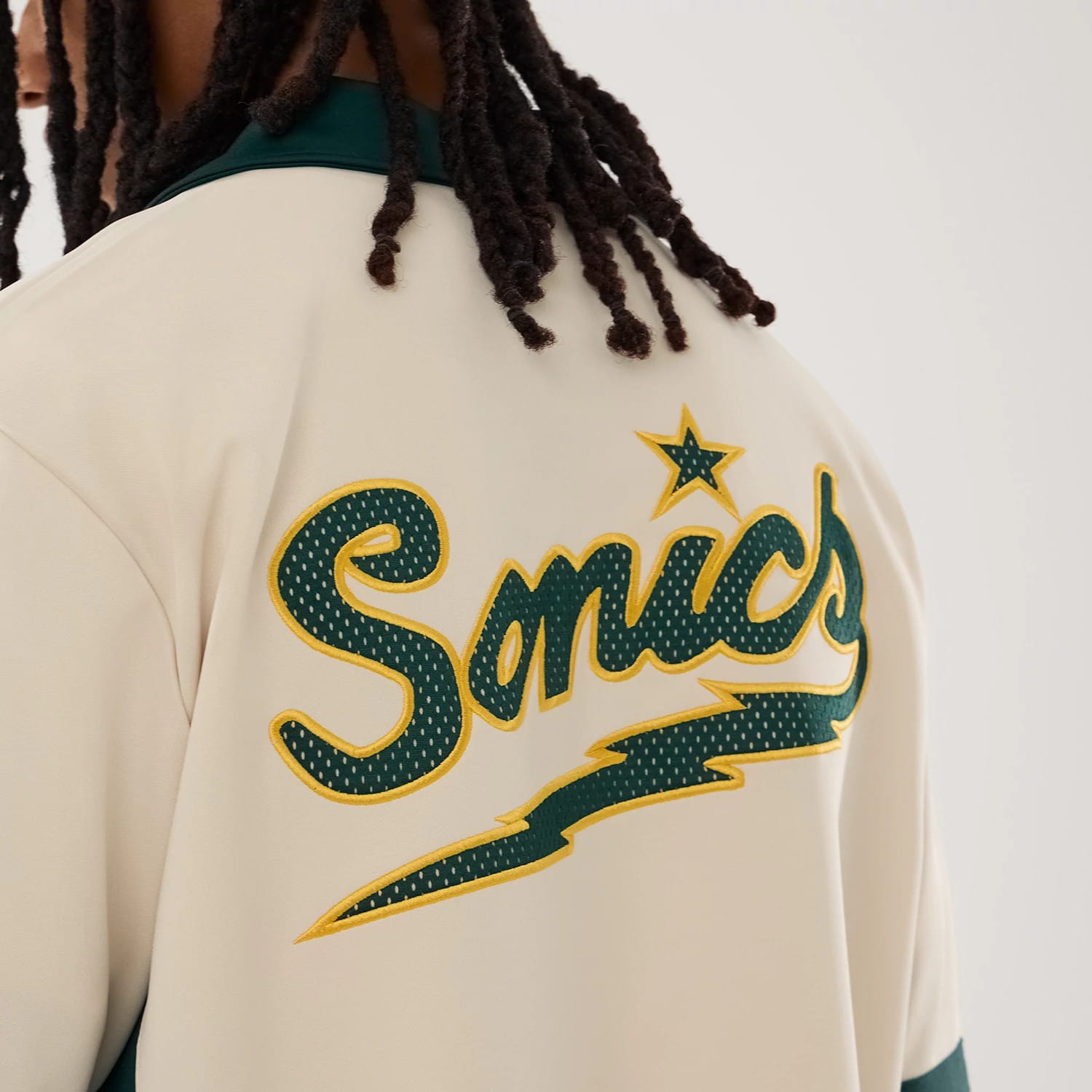The model is wearing this NBA Hardwood Classic Revere Seattle Supersonics Short Sleeve Shirt in light beige. 7