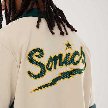 The model is wearing this NBA Hardwood Classic Revere Seattle Supersonics Short Sleeve Shirt in light beige. 7