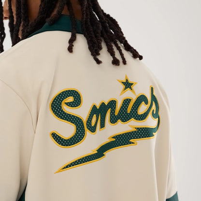 New Era Supersonics NBA Hardwood Classic Revere Beige Short Sleeve Shirt, back view on a model featuring a large green and yellow embroidered Sonics script with a star above it on the upper back, complemented by a dark green collar.