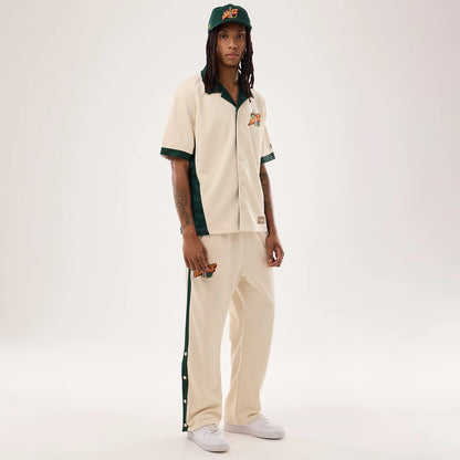 The model is wearing this NBA Hardwood Classic Revere Seattle Supersonics Short Sleeve Shirt in light beige. 8
