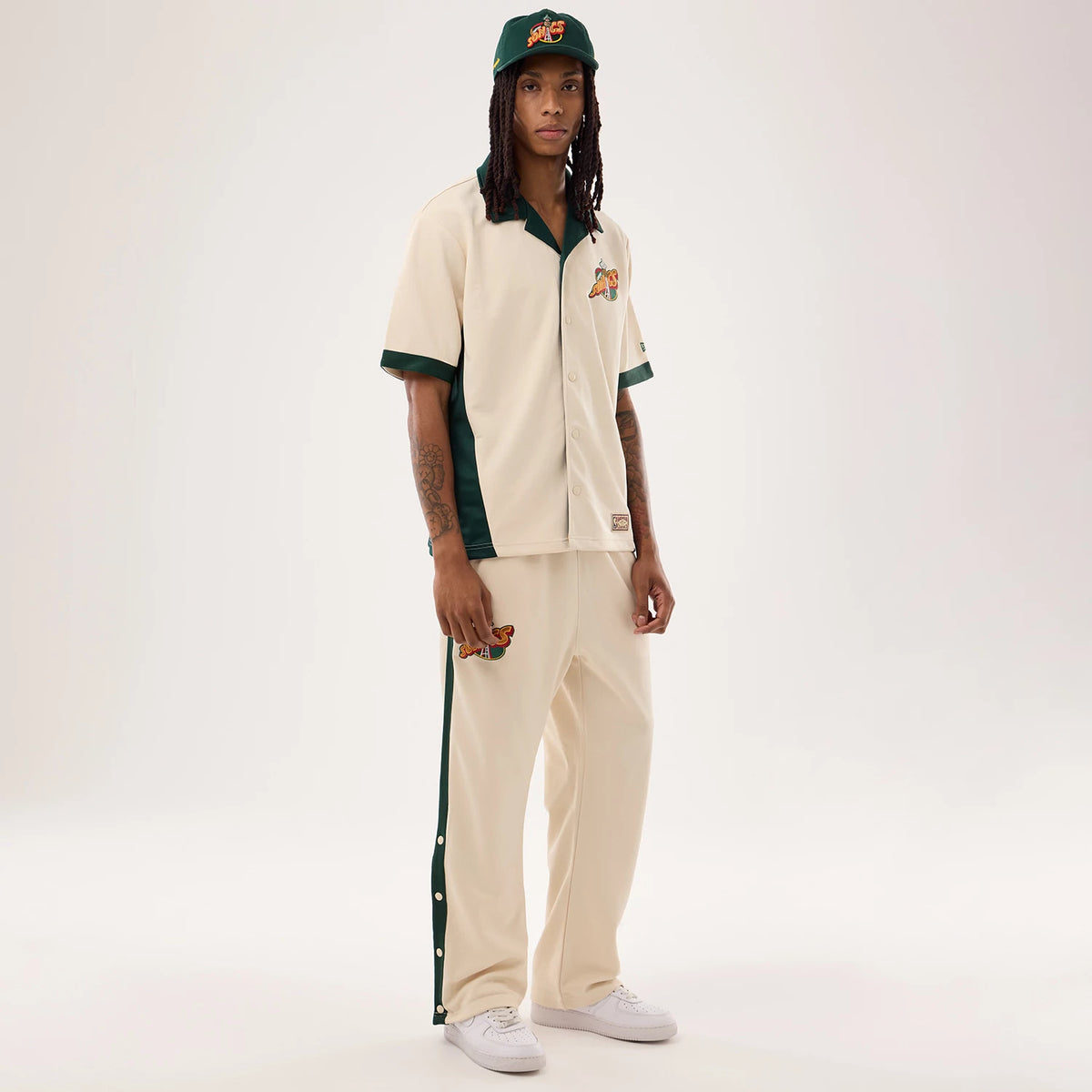 New Era Supersonics NBA Hardwood Classic Revere Beige Short Sleeve Shirt, on-model front view showing a relaxed fit with green trim along the collar and sleeves, an embroidered team logo on the chest, and button closure down the front.