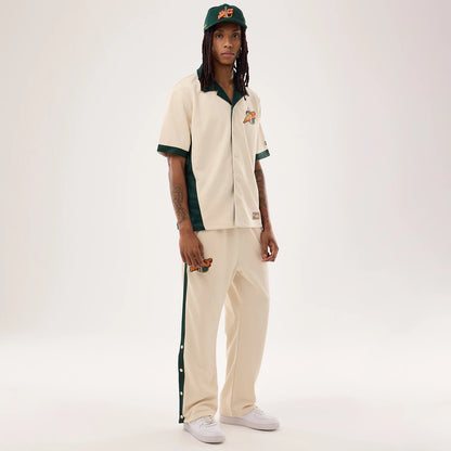New Era Supersonics NBA Hardwood Classic Revere Beige Short Sleeve Shirt, on-model front view showing a relaxed fit with green trim along the collar and sleeves, an embroidered team logo on the chest, and button closure down the front.
