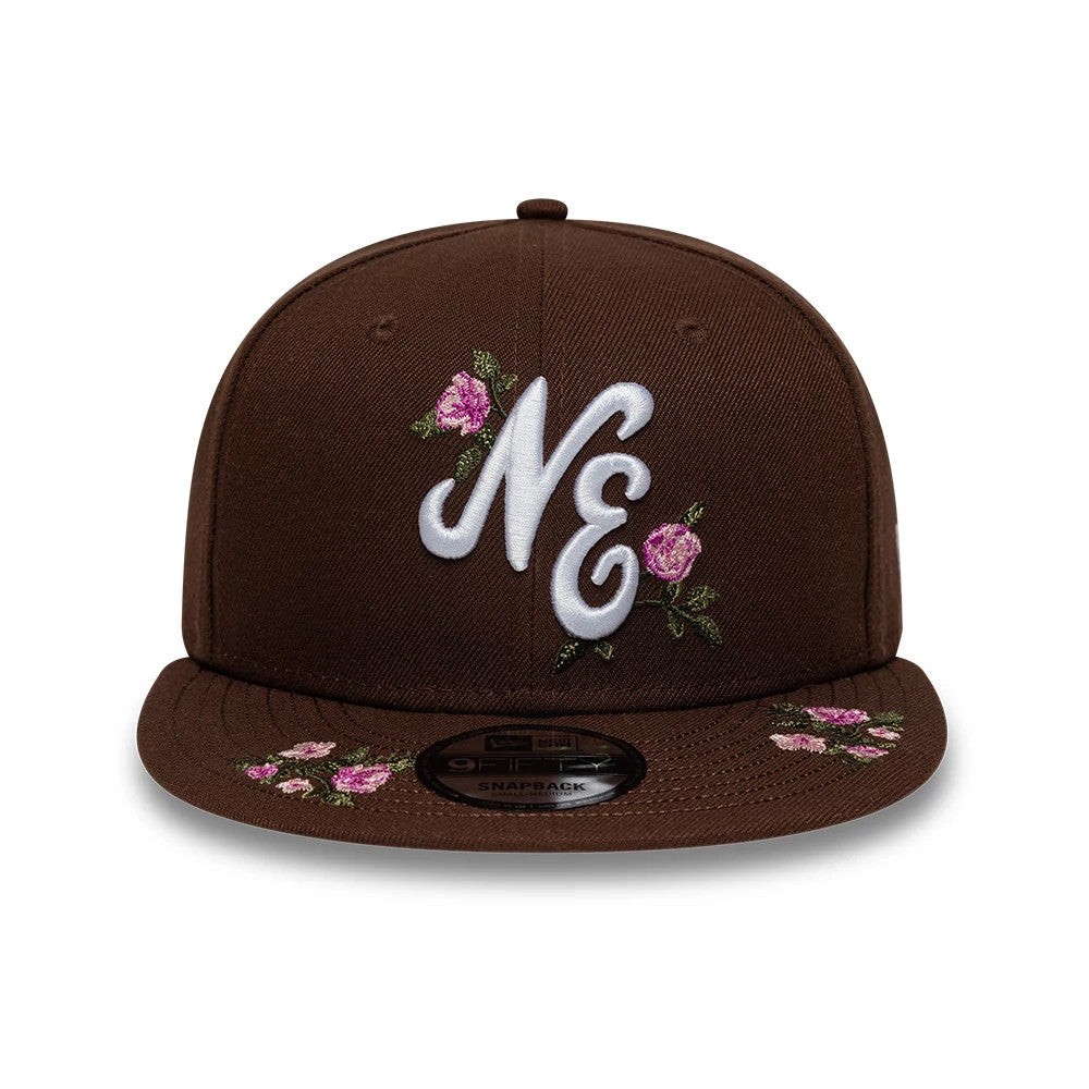 New Era Floral Dark Brown 9FIFTY Snapback Adjustable Cap, front view showing raised white embroidered NE lettering with pink floral on the front panel, matching floral design on the visor, and 9FIFTY size sticker on the visor.