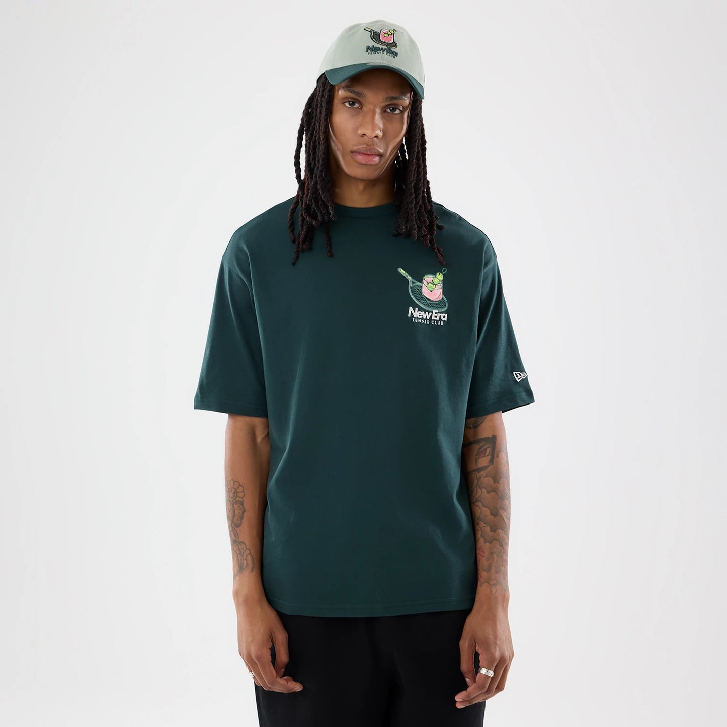The model is wearing this New Era Tennis Graphic Oversized T-Shirt in dark green. 1