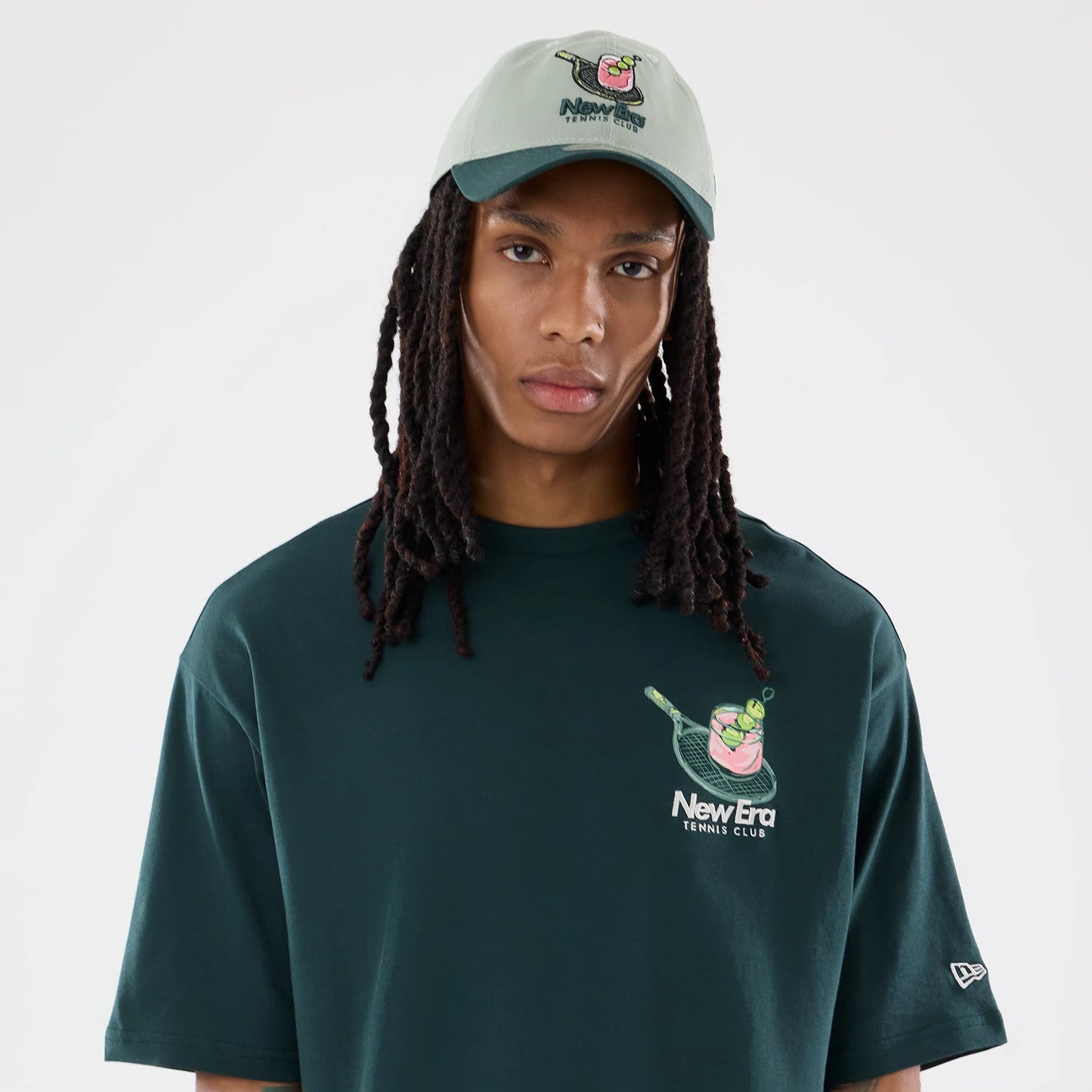 The model is wearing this New Era Tennis Graphic Oversized T-Shirt in dark green. 3