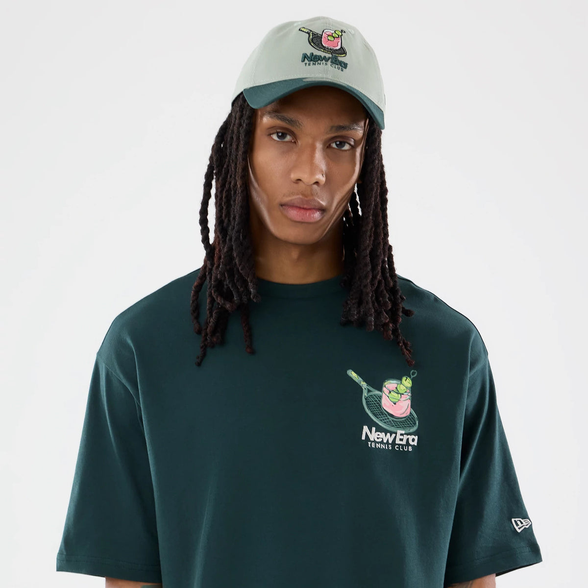 New Era Tennis Graphic Oversized Dark Green T-Shirt, front view on-model displaying a printed tennis graphic on the left chest, New Era Tennis Club lettering beneath, and a embroidered New Era flag logo on the left sleeve.