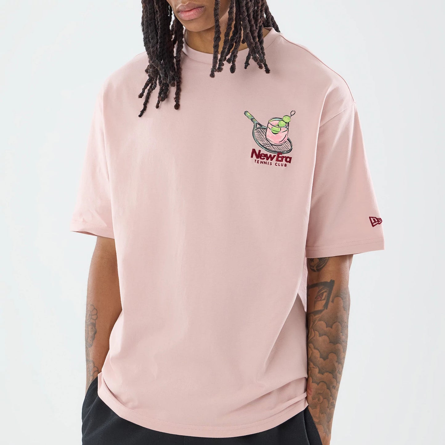 The model is wearing this New Era Tennis Graphic Oversized T-Shirt in pastel pink. 5