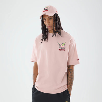 The model is wearing this New Era Tennis Graphic Oversized T-Shirt in pastel pink. 1