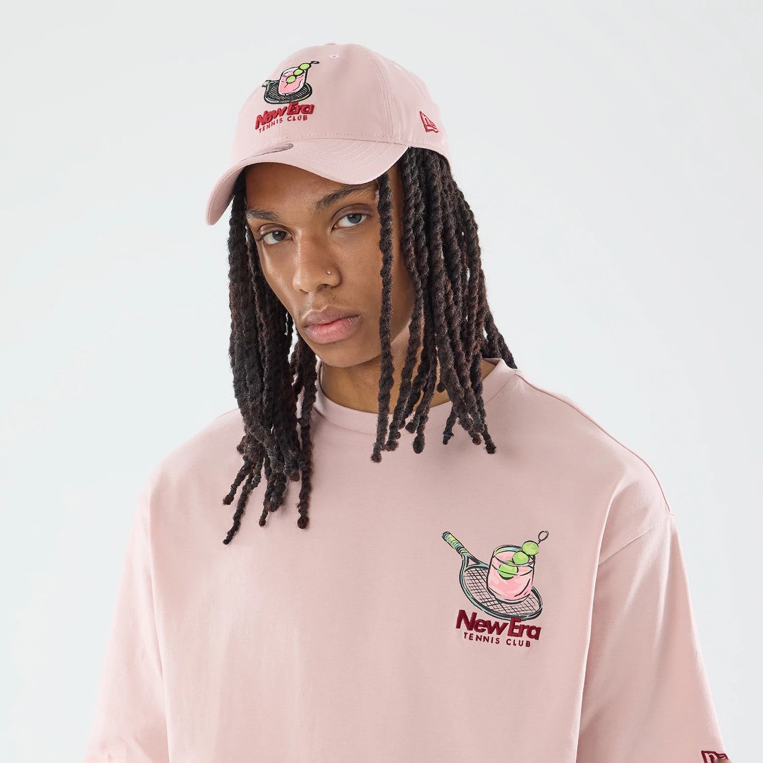 The model is wearing this New Era Tennis Graphic Oversized T-Shirt in pastel pink. 3