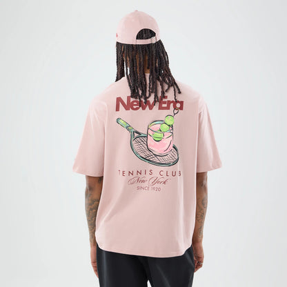 The model is wearing this New Era Tennis Graphic Oversized T-Shirt in pastel pink. 2